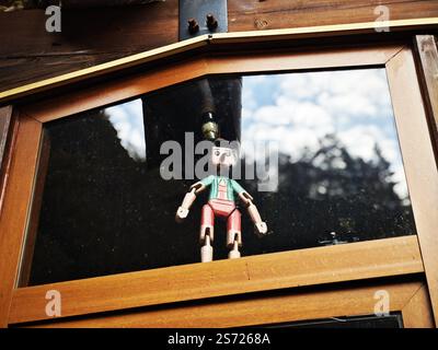 Eine Vintage Pinocchio-Puppendekoration aus Holz, die am Glasfenster hängt Stockfoto