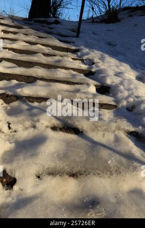 Gefährliche Stufen von ungeklärten Straßentreppen, die stark mit Eis und Schnee bedeckt sind Stockfoto