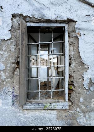 Verruiniertes Fenster mit Metallstangen an einer verlassenen Hausfassade, Blick von vorne Stockfoto