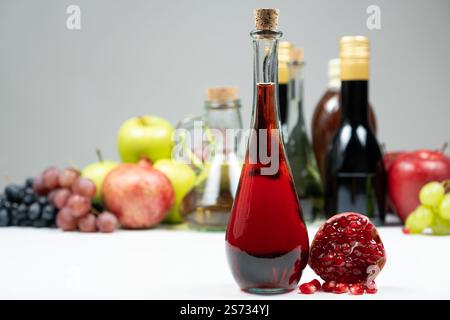 Granatapfelessig vor dem Hintergrund von Früchten und anderen Essigsorten Stockfoto