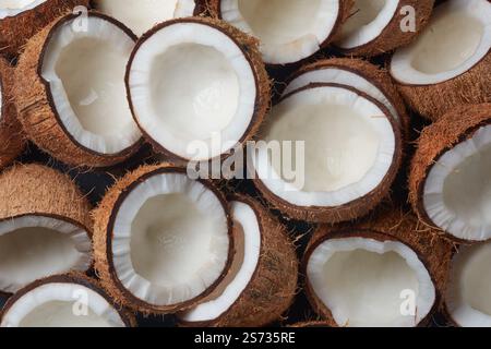 Kokosnussstapel in zwei Hälften bei Nahaufnahme, braune Faserschale und inneres weißes Fleisch sichtbar, Fülle und Frische Konzept Stockfoto