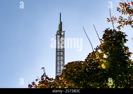 Im Hintergrund ist ein hoher Turm mit einem Baum zu sehen. Der Baum hat Blätter, die ihre Farbe ändern, was dem Bild ein Gefühl des Herbstes verleiht. T Stockfoto