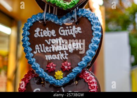 Drei Schokoladenherzen mit Zuckerguss und den Aufschriften „Liebe Gruesse vom Allerheiligen Markt“. Die Herzen hängen an einem Stab Stockfoto