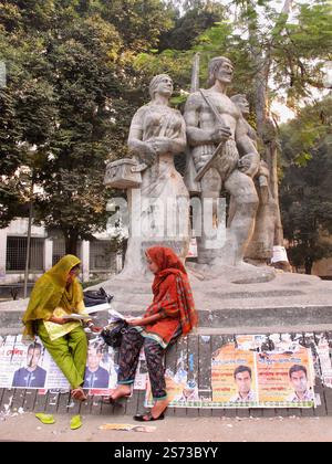 Zwei Studentinnen lesen am Aparajeyo Bangla Monument der Universität Dhaka, das Bangladeschs Befreiungskrieg und die akademische Kultur symbolisiert. Stockfoto