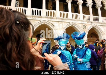 VENEDIG, ITALIEN - 14. FEBRUAR 2015: Touristen machen während des Karnevals Fotos von zwei Masken auf dem Markusplatz. Der Karneval in Venedig findet jährlich statt Stockfoto