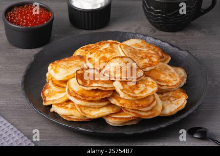 Köstlicher Stapel goldener Pfannkuchen, serviert mit Sahne und Kaviar auf einem rustikalen Tisch Stockfoto
