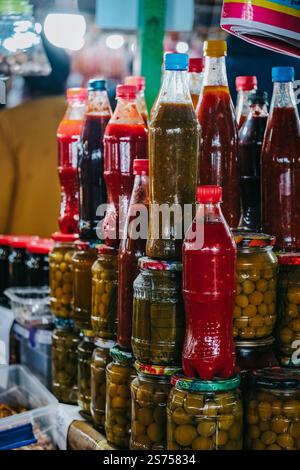 Nahaufnahme hausgemachter Gurken und Ketchup, abgefüllt in Glasgläsern oder Plastikflaschen auf dem Telavi Bazaar, dem Markt der Stadt Telavi, Georgia Stockfoto