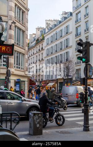 Straßenszene in Paris mit Menschen, Verkehr und U-Bahn-Schildern mit klassischer Pariser Architektur und geschäftigem Treiben im Dezember. Stockfoto