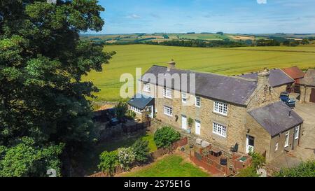 Drohnenansicht des britischen Bauernhofs mit Steinhäusern umgeben von grünen Feldern northumberland uk Erbschaftssteuer] Stockfoto