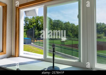 Das Innere eines Pressekastens mit einem Mikrofon mit einigen von einem synthetischen Rasen-Baseballfeld. Stockfoto