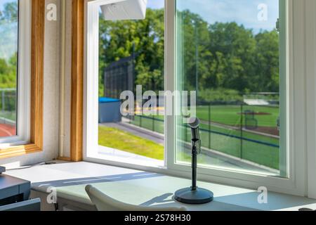 Das Innere eines Pressekastens mit einem Mikrofon mit einigen von einem synthetischen Rasen-Baseballfeld. Stockfoto