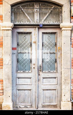 Rustikale Holztür mit Metallgitter und roter Ziegelwand. Stockfoto