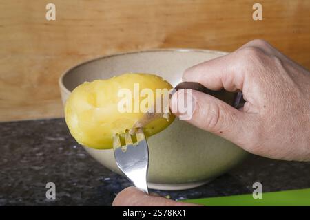 Schwäbische Küche, Zubereitung von schwäbischem Kartoffelsalat mit Stuttgarter Leberkaes in Meerrettich-Senfüberzug, Schälen gekochter Kartoffeln, Pota-Mantelmantel Stockfoto