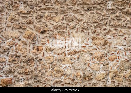 Detaillierter Blick auf die rustikale Steinmauer mit gemischten Texturen und Erdtönen. Stockfoto