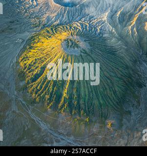 Morgensonne aus der Vogelperspektive, die gegen den Bergrücken der Bromo-Vulkangruppe plätschert. Der weiße Rauch, der immer noch aus dem Bromo-Krater aufsteigt, zieht weiter. Nahaufnahme Stockfoto
