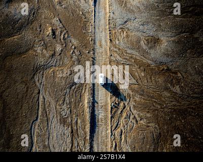Blick auf die Drohne eines Autos, das auf einer Schotterstraße in einer Wüstenlandschaft in der Nähe von Landmannalaugar, den Rainbow Mountains in Island, fährt Stockfoto