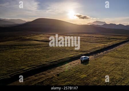 Geländewagen, der durch die malerische Landschaft bei Sonnenuntergang in der Nähe von Landmannalaugar fährt, genannt Rainbow Mountains in Island Stockfoto