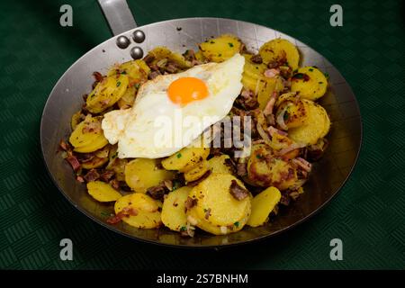 Tiroler Groestl traditionelles Tiroler Frittieren mit Kartoffeln, Fleisch und gebratenem Ei im Landhausstil in einer Stahlpfanne Stockfoto
