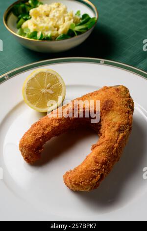 Paniertes und frittiertes Karpfensteak mit Mayonnaise-Kartoffelsalat und einer Zitrone Stockfoto