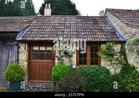 Park Lane typisches englisches Steinhaus mit spitzen Dächern aus dunklen Fliesen und Kletterpflanzen. Castle Combe Village, Cotswolds, England, Großbritannien Stockfoto