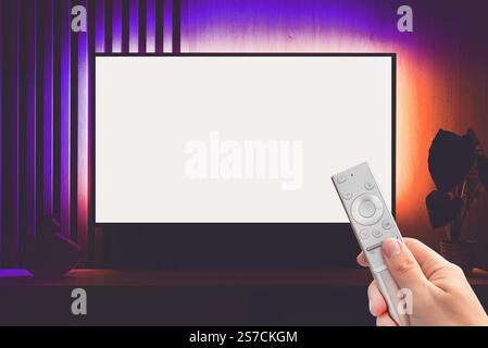 Moderne Wohnzimmereinrichtung mit leerem Smart-TV. TV-Konzept, Fernbedienung in der Hand Stockfoto