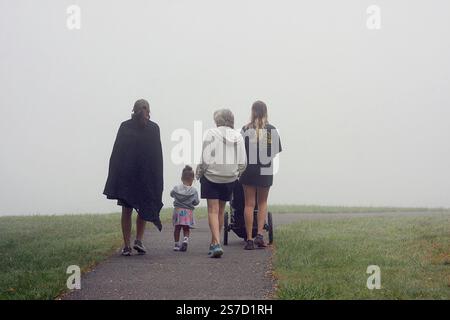Virginia, USA. Frauen mit kleinen Kindern, die an einem nebeligen Morgen auf einem Wanderweg laufen. Stockfoto