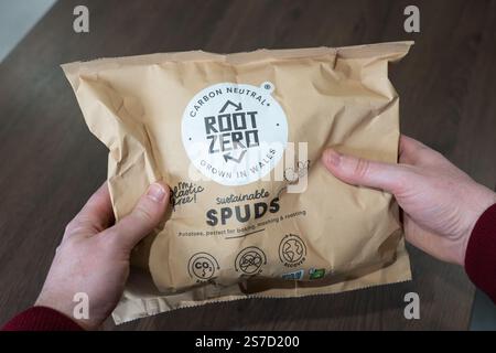 Mann mittleren Alters mit Wurzel Zero nachhaltige Spuds (Kartoffeln), angebaut in Wales ohne Plastikpapierverpackung und kohlenstoffneutral, Großbritannien Stockfoto