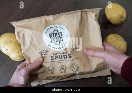 Mann mittleren Alters mit Wurzel Zero nachhaltige Spuds (Kartoffeln), angebaut in Wales ohne Plastikpapierverpackung und kohlenstoffneutral, Großbritannien Stockfoto