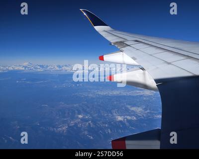 Atemberaubender Blick aus der Luft auf die schneebedeckten Berge von einem Flugzeugfenster aus Stockfoto