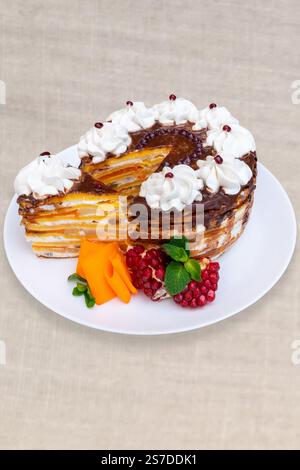 Ein wunderschön gestalteter Kuchen besteht aus Schokoladenfrosting, leuchtenden Fruchtschichten und wird mit Schlagsahne garniert. Garniert mit frischem Obst Stockfoto