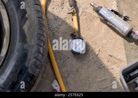 Diese Abbildung zeigt eine Nahaufnahme einer Reifenwartung auf sandiger und kiesiger Oberfläche. Stockfoto