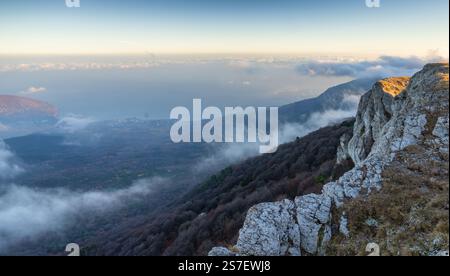 Atemberaubender Blick auf die Berge, die im Morgennebel bedeckt sind, mit einem lebendigen Himmel bei Sonnenaufgang Stockfoto