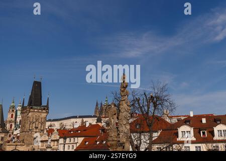 Prag, Tschechische republik - 16. März 2023: Steinstatue auf der karlsbrücke mit prager Burg und St. Vitus-Kathedrale im Hintergrund auf einer Sonne Stockfoto