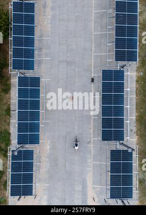 Draufsicht einer Person, die zwischen über Parkplätzen installierten Sonnenkollektoren radelt Stockfoto