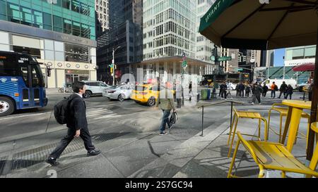 Ein geschäftiger New Yorker Morgen an der Kreuzung von West 42nd Street und Bryant Park. Fußgänger überqueren die Straße. Stockfoto