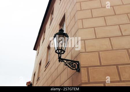 Eine alte schwarze Laterne mit Glas an der gelben rauen Wand eines Hauses in Praha, Tschechien Stockfoto