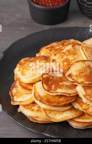 Köstlicher Stapel goldener Pfannkuchen, serviert mit Sahne und Kaviar auf einem rustikalen Tisch Stockfoto