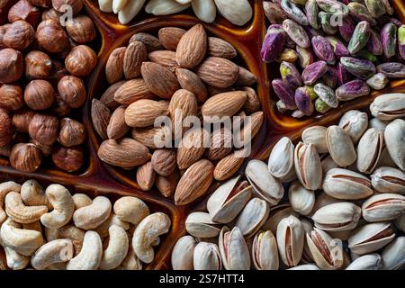 Nusssortiment in Keramikschale, Nahaufnahme, Draufsicht. Cashew, Haselnüsse, Pistazien und Mandelnüsse zum Essen. Vegetarische Mahlzeit. Gesunde Ernährung im Geheimen Stockfoto
