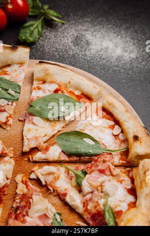 Handgemachte Pizzablätter mit Spinat, Mandeln und Basilikumblättern auf einem rustikalen Holzteller Stockfoto