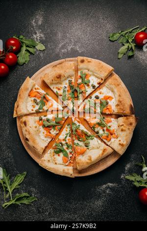 Geschnittene Gourmet-Pizza mit Räucherlachs, Rucola und Kapern auf einem rustikalen Holzbrett Stockfoto