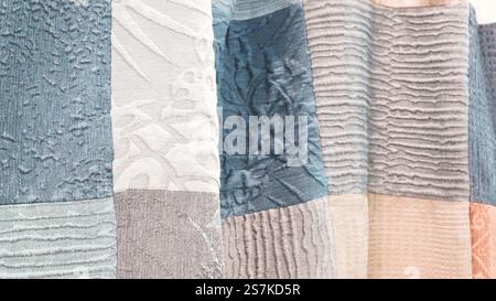 In einer Reihe werden verschiedene farbige Stoffteile angezeigt. Die Farben sind Blau, Grau und weiß. Die Anordnung der Teile schafft Stockfoto