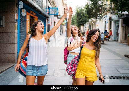 Drei junge Frauen, die lachen und High-Five auf einer Stadtstraße geben Stockfoto