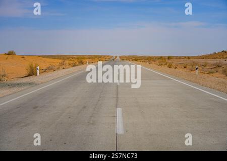 Symmetrische Ansicht der Autobahn A380, die durch die Kyzylkum-Wüste, Chorezm, Usbekistan, Zentralasien führt Stockfoto