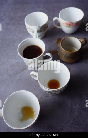 Eine vielfältige Sammlung leerer und gebeizter Kaffeetassen, die auf einem Tisch sitzen Stockfoto