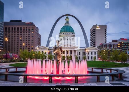 St. Louis, MO USA - 13. April 2019: Die Runner-Statue hinter dem Brunnen beleuchtet von roten Lichtern im Kienar Park mit dem Gateway Arch im Hintergrund. Stockfoto