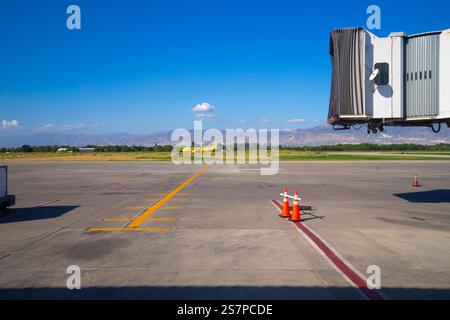 Sonnenaufgangsflugzeuge fliegen im Hintergrund, eingerahmt von einem leeren Jetway, der darauf wartet, dass das nächste Flugzeug am Flughafen Port-Au-Prince ankommt Stockfoto