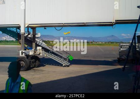 Sonnenaufgangsflugzeuge fliegen im Hintergrund, eingerahmt von einem leeren Jetway, der darauf wartet, dass das nächste Flugzeug am Flughafen Port-Au-Prince ankommt Stockfoto