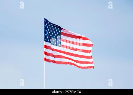 Amerika-Flagge am blauen Himmel mit Beschneidungspfad. Nahaufnahme, die Flagge Amerikas schwenkt. Flaggensymbole von Amerika. Stockfoto