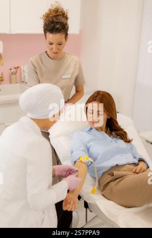 In einer einladenden Klinik zieht ein medizinisches Fachpersonal geschickt Blut von einem Patienten, während ein anderer Fachmann Unterstützung leistet und eine Atmosphäre schafft Stockfoto