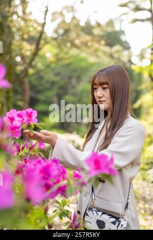Eine Japanerin im Alter von 20 Jahren, die weiße Kleidung trägt, verbringt Zeit in einem Naturpark in Japan. Stockfoto